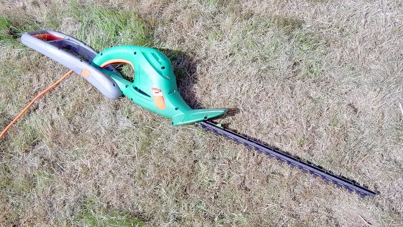 Elektrische Heckenschere an einer frisch geschnittenen Hecke